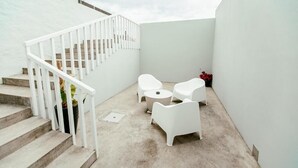 Eine moderne Außenpatio mit weißer Möbel, einer Treppe und einem Betonboden.