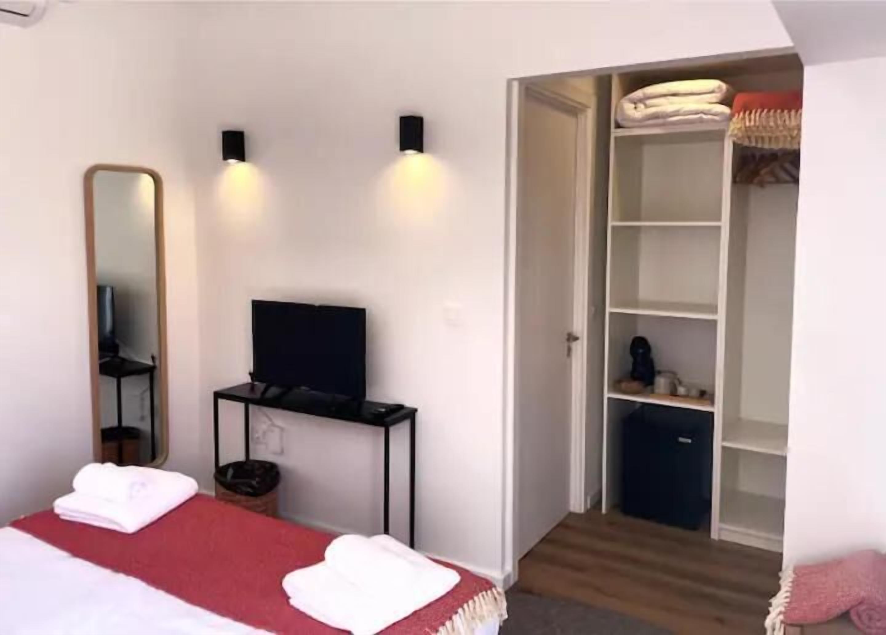 Ein Schlafzimmer mit einem Bett, einem Fernseher auf einem Schrank, einem Kleiderschrank und einem Spiegel.