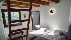 Ein Schlafzimmer mit Etagenbett, einer Sprossenleiter, einem Fenster, einem Spiegel und einer Wandleuchte.
