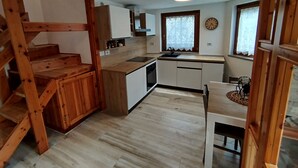 Eine kleine Küche mit Holzelementen, einem eingebauten Spülbecken und einem Fenster mit Spitzenvorhängen.