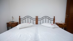 A double bed with a wooden headboard, two bedside tables with lamps, and a wooden wardrobe. - Lesvos Garden Escape - A Serene Escape in Nature (Vatoussa)