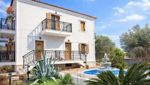 A two-story building with a white exterior, wooden shutters, and a balcony with black railings. - Lesvos Garden Escape - A Serene Escape in Nature (Vatoussa)