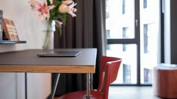 Ein stilvoller Essbereich mit einem Holztisch, einem roten Stuhl und einer Vase mit Blumen.