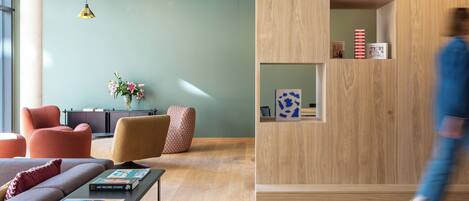 Un interior moderno con un mostrador de recepción de madera, un sofá y una mesa de centro con libros.