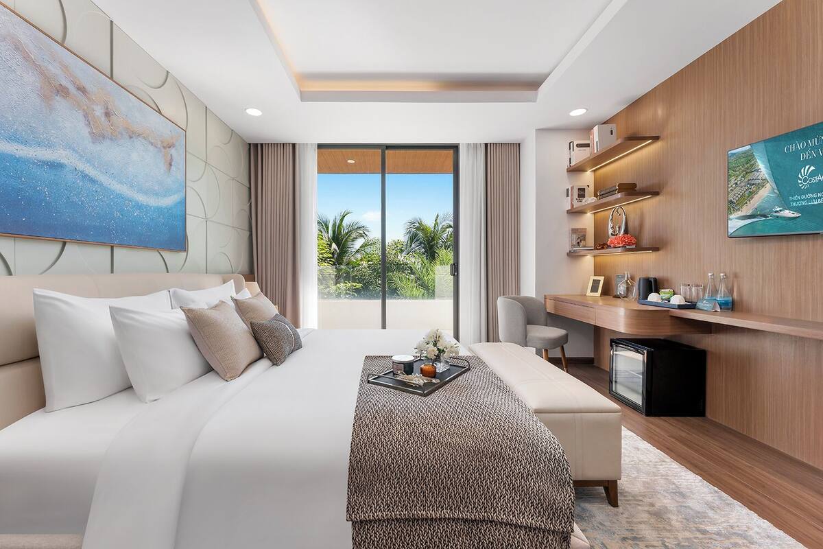 Une chambre d’hôtel moderne, dotée d’un grand lit, d’un bureau, d’une télévision et offrant une vue sur l’extérieur.
