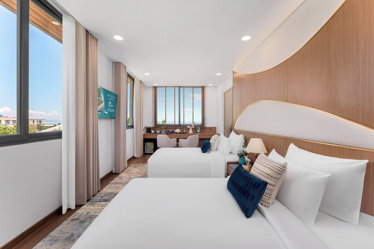 Une chambre d’hôtel avec deux lits, un bureau et une vue sur la ville.