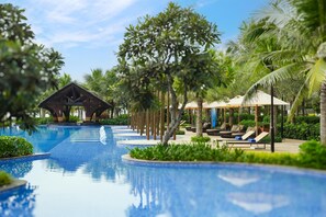 A pool area with lounge chairs and umbrellas, surrounded by palm trees and a clear sky. - Costamigo Phan Thiet, Bw Premier Collection (Tan Thanh)