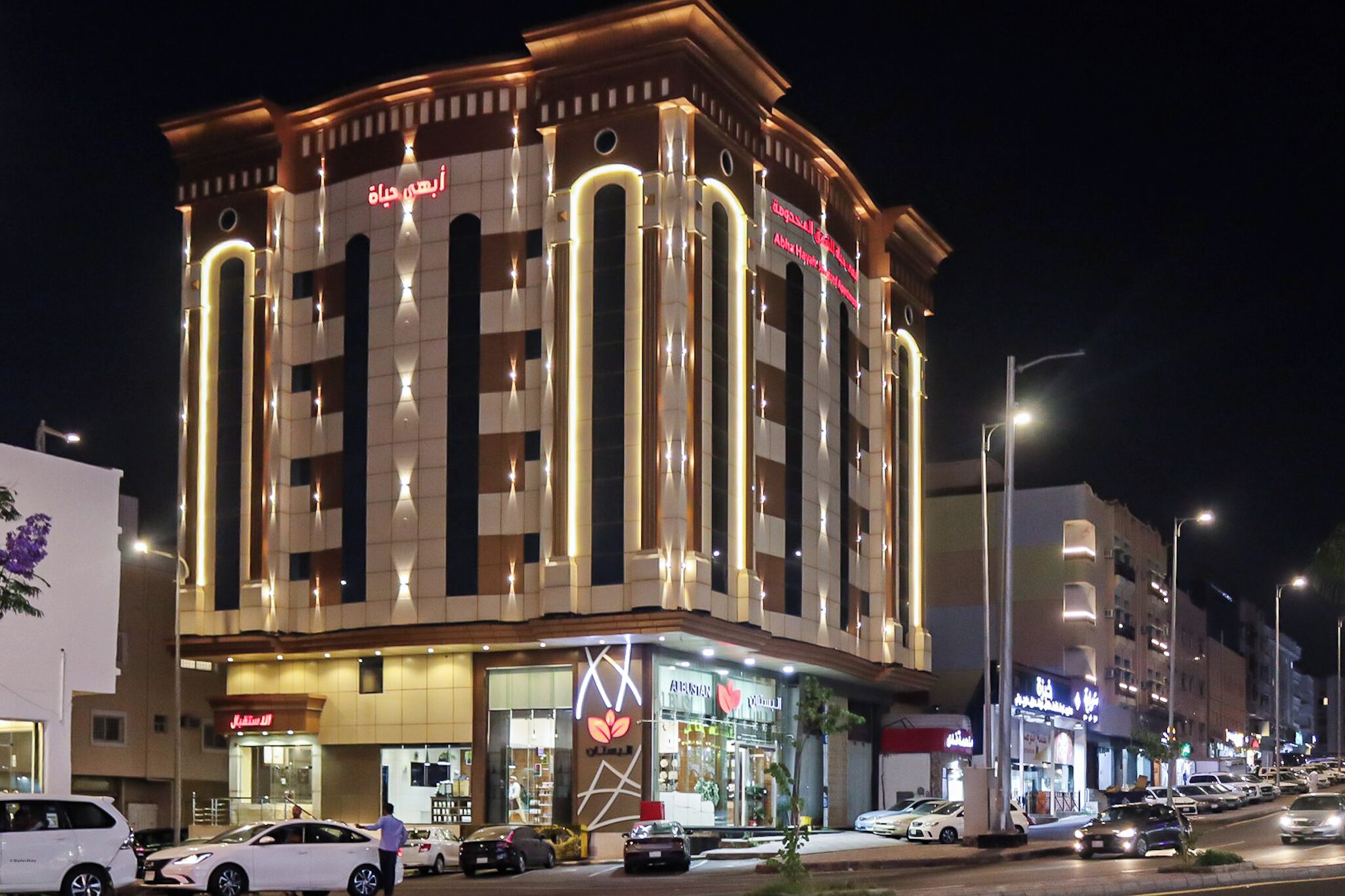 A multi-story hotel with a modern facade, illuminated signage, and a ground-level retail space.