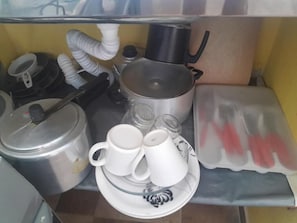 A kitchen area with a stove, pots, a kettle, and a coffee maker. - Family Studio (Santa Cruz Cabrália)