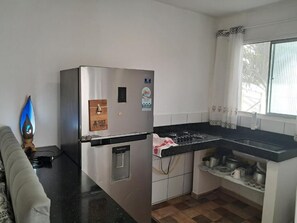 A compact kitchen with a refrigerator, stove, and sink. - Family Studio (Santa Cruz Cabrália)