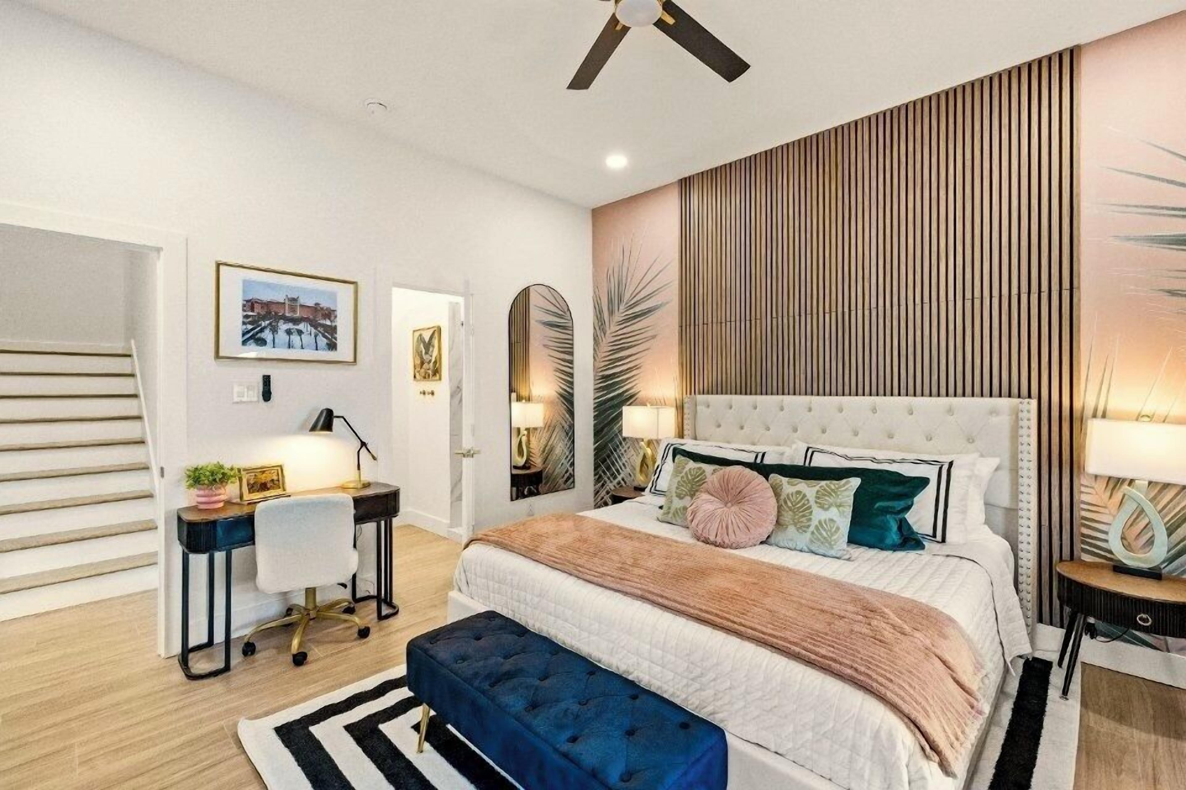 A bedroom with a bed, bedside tables, a desk, and a chair.