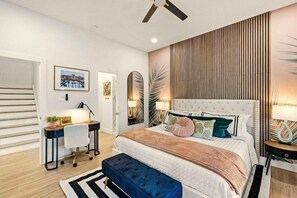 A bedroom with a bed, bedside tables, a desk, and a chair. - Beach House | Swim Spa, Hot Tub, Mini Golf, Games (Galveston)