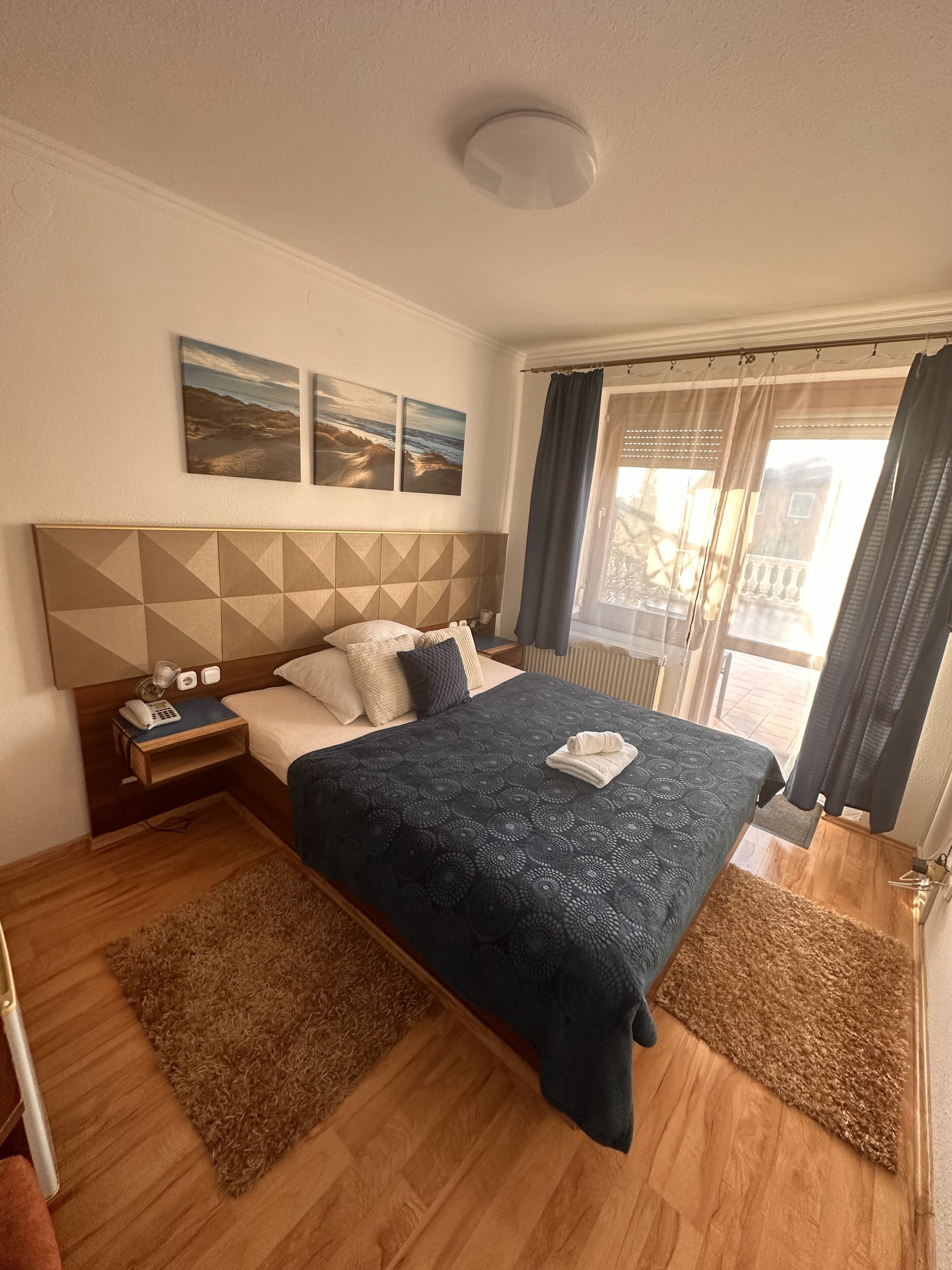 Un dormitorio con cama, mesita de noche y vistas al exterior.