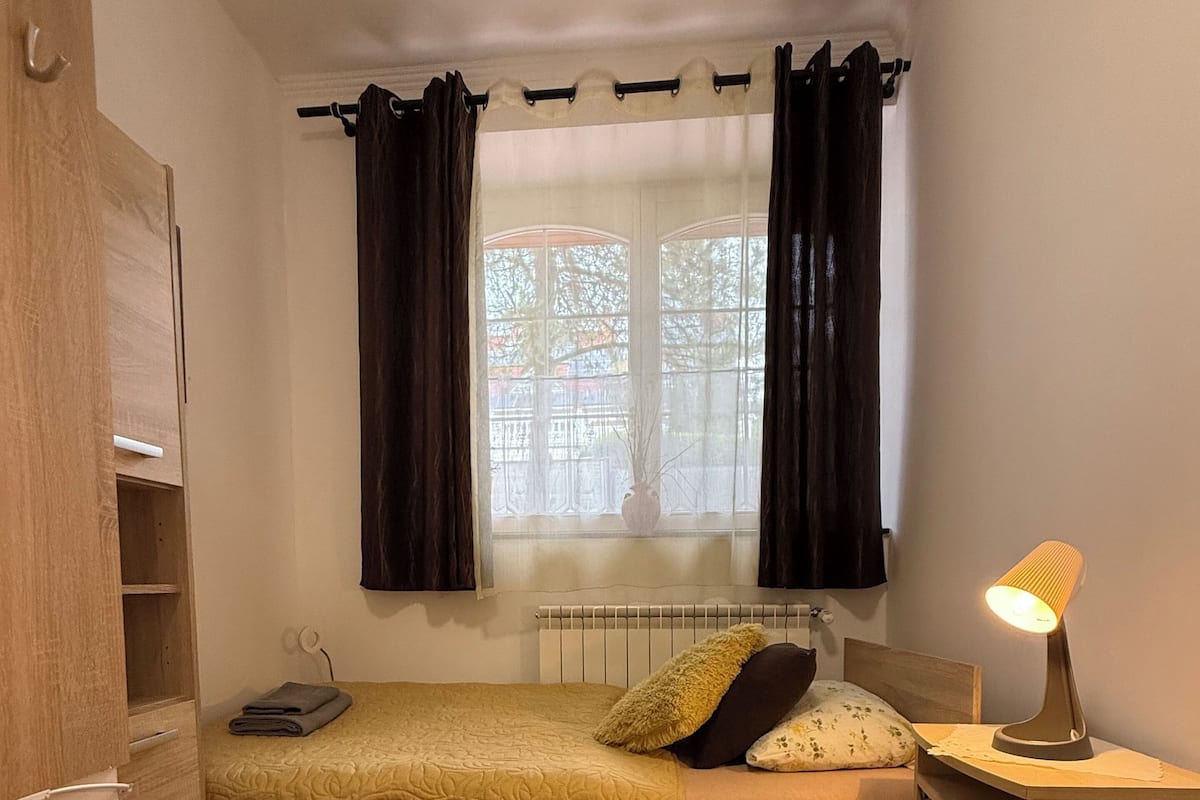 Ein kleines, ordentlich eingerichtetes Schlafzimmer mit einem Bett, einem Nachttisch und einem Heizkörper.