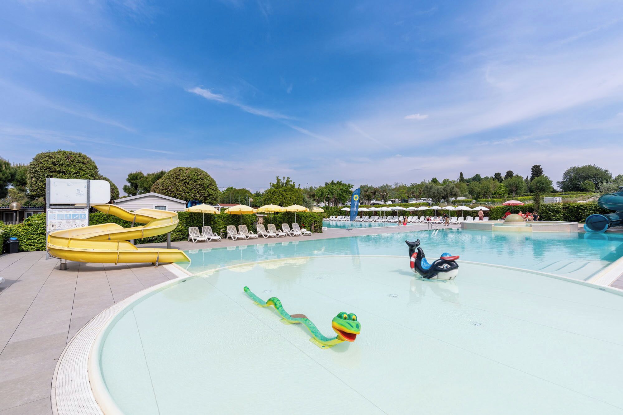 A swimming pool with slides, lounge chairs, and a water slide.