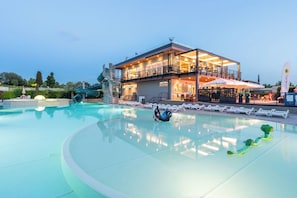 Un hotel moderno con piscina, scivolo acquatico e ristorante.