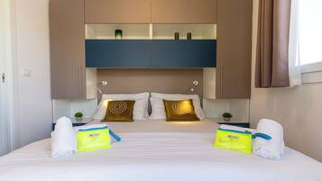 A hotel room with a bed, two bedside tables, a built-in shelf above the bed, and a window with curtains.