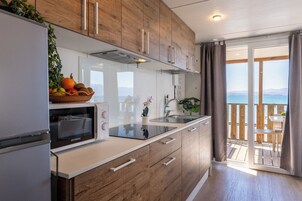 Una cucina moderna con forno integrato, lavello e vista mare da un balcone.