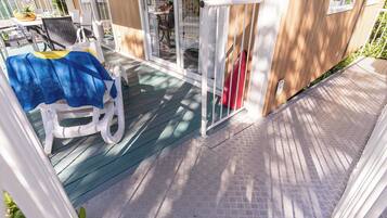 Un espacio al aire libre cubierto con una mesa de patio y sillas, una puerta corrediza de vidrio y una terraza de madera.
