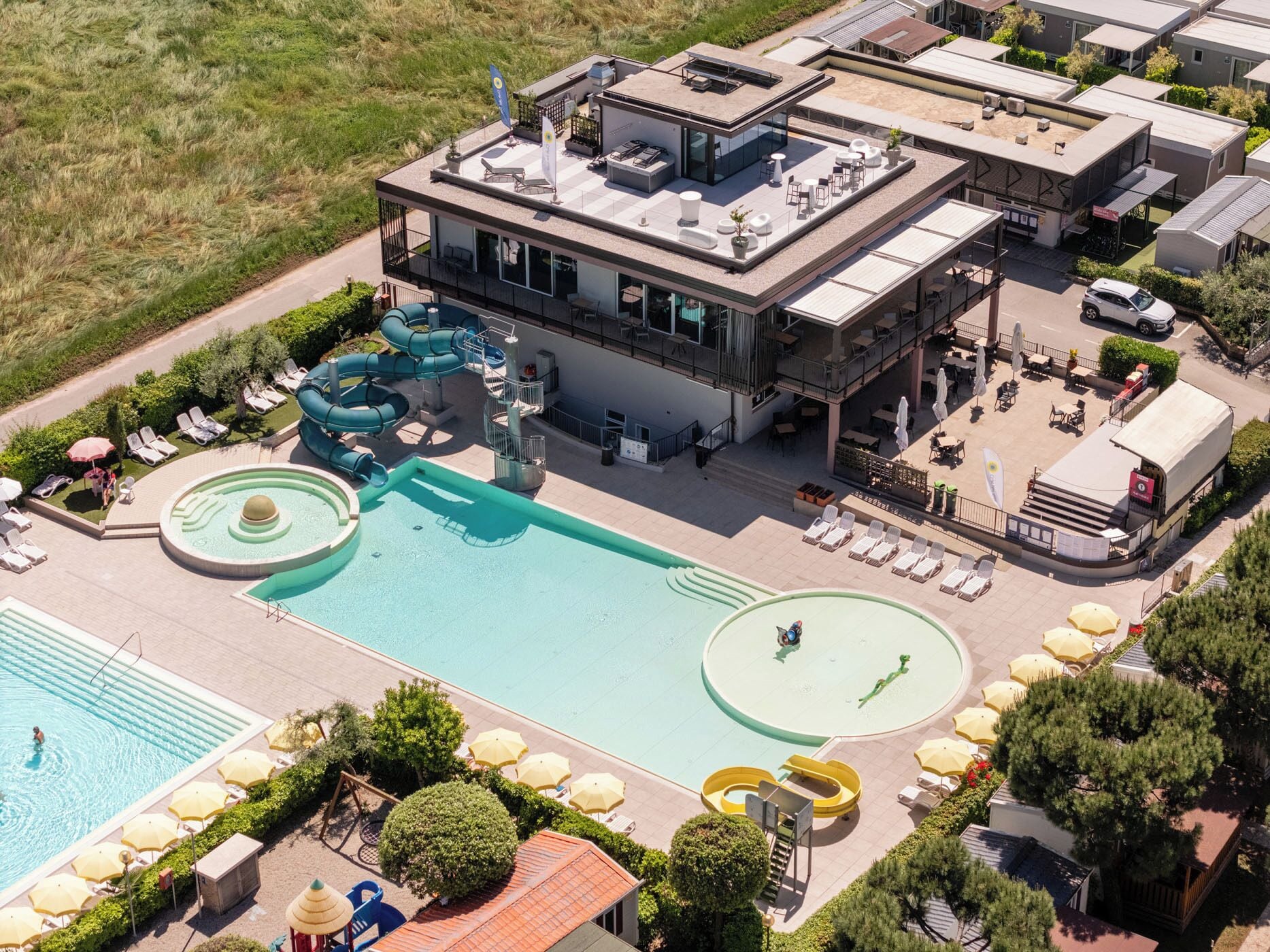 A modern hotel with a rooftop pool, a water slide, and a separate swimming pool area.
