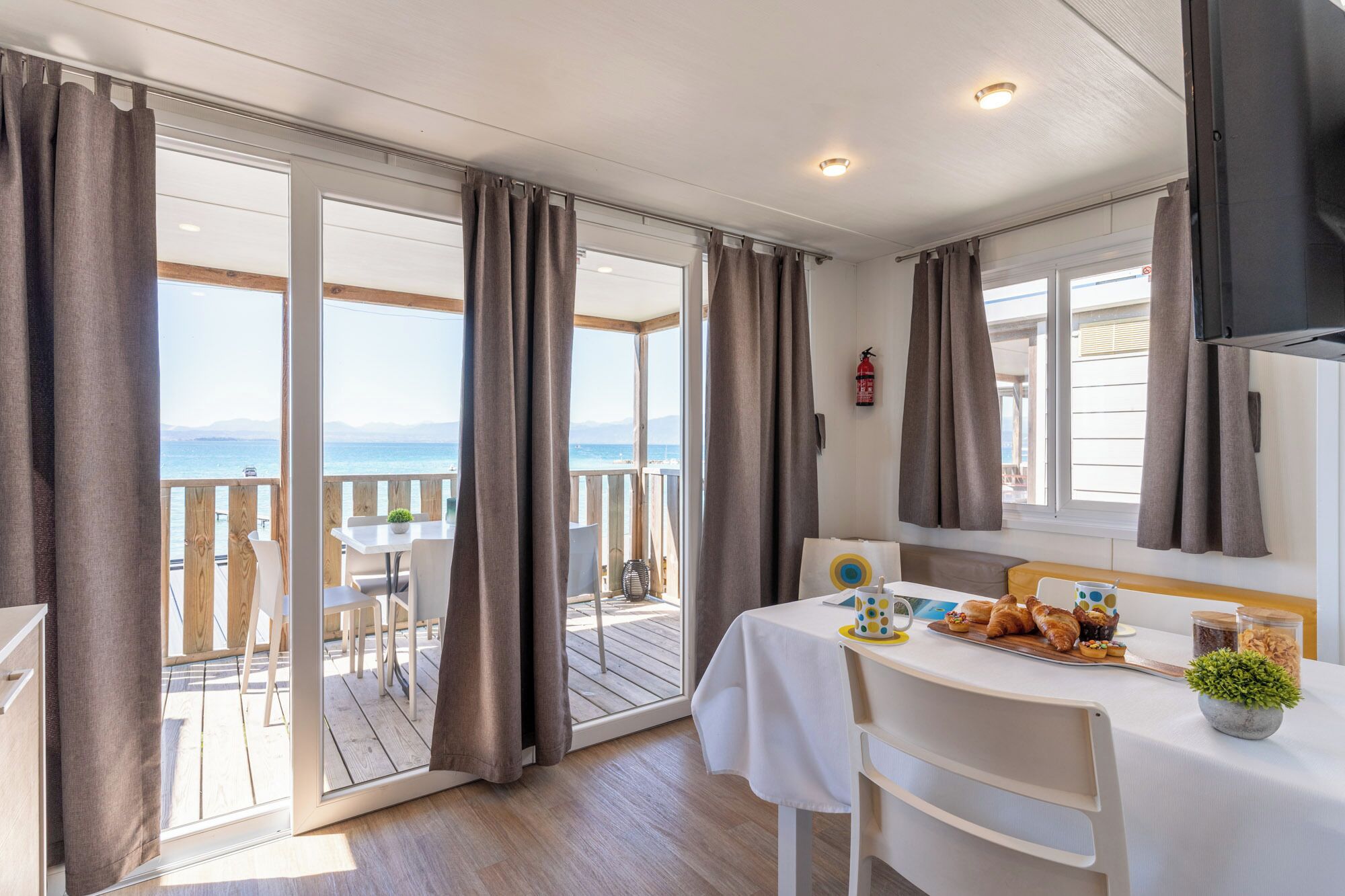 Quarto com varanda, mesa com comida e vista para o mar.