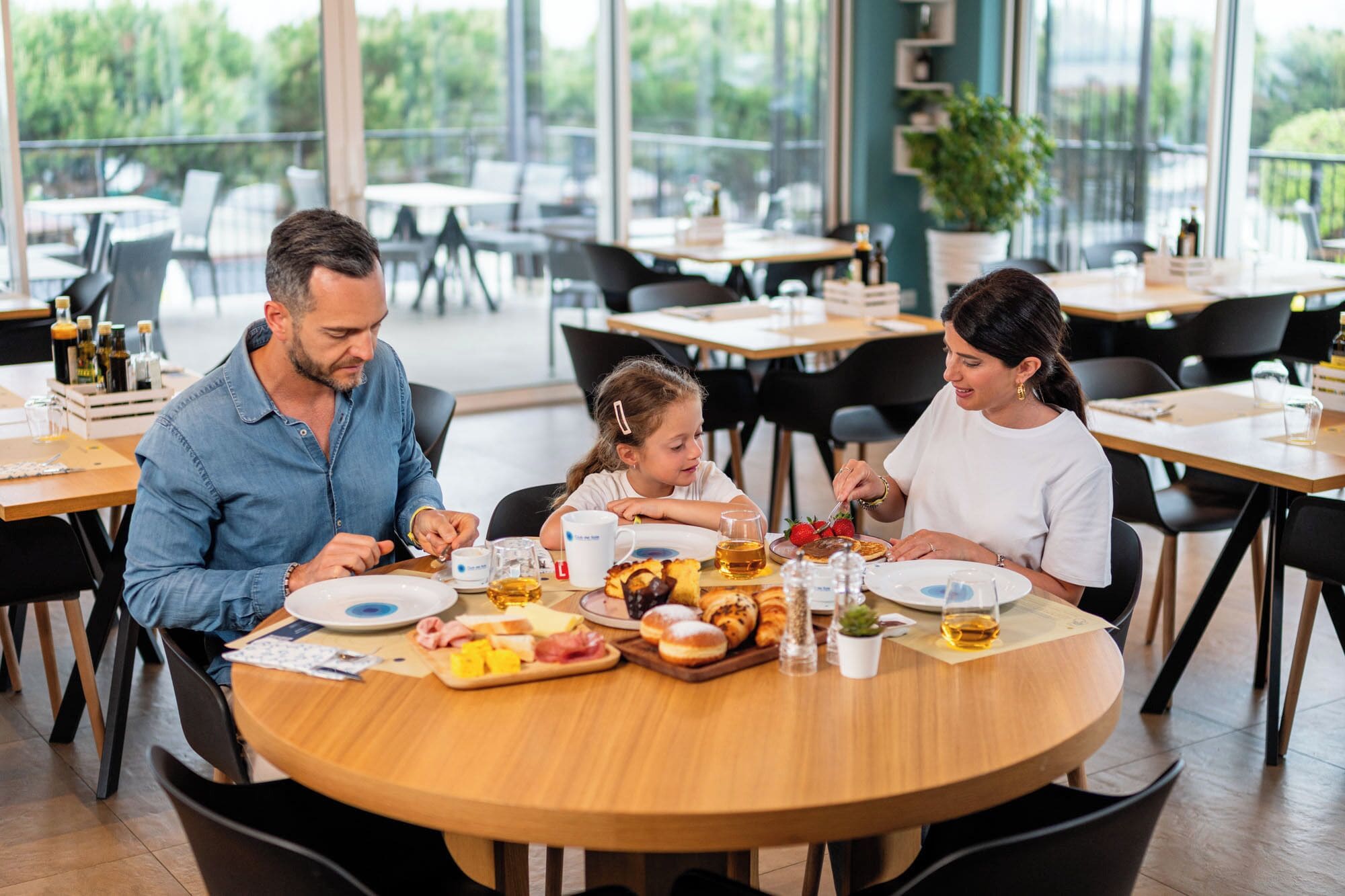 Una familia cenando en una mesa redonda con diversos alimentos y bebidas.