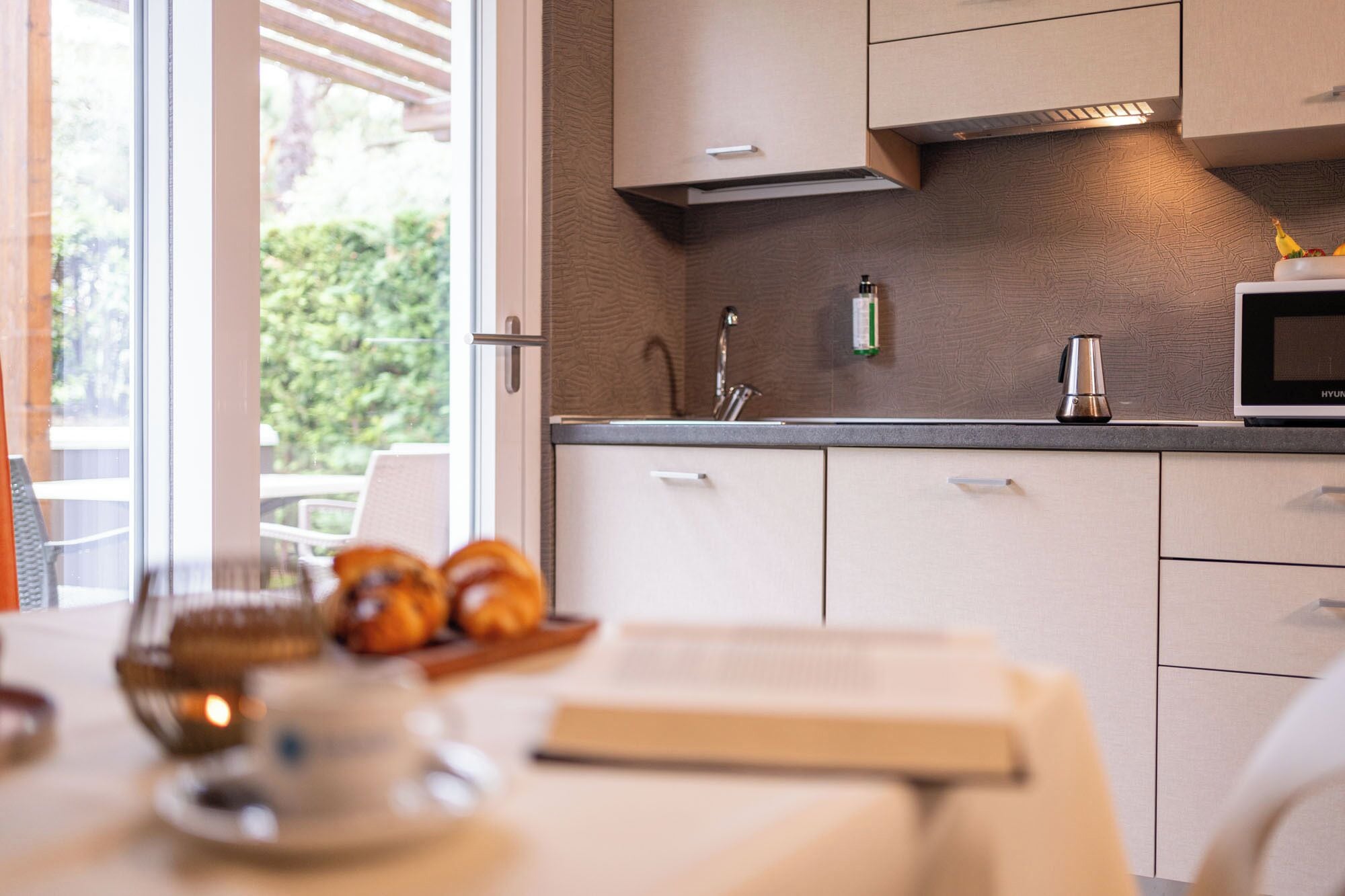 A modern kitchen with a microwave, sink, and stainless steel kettle.