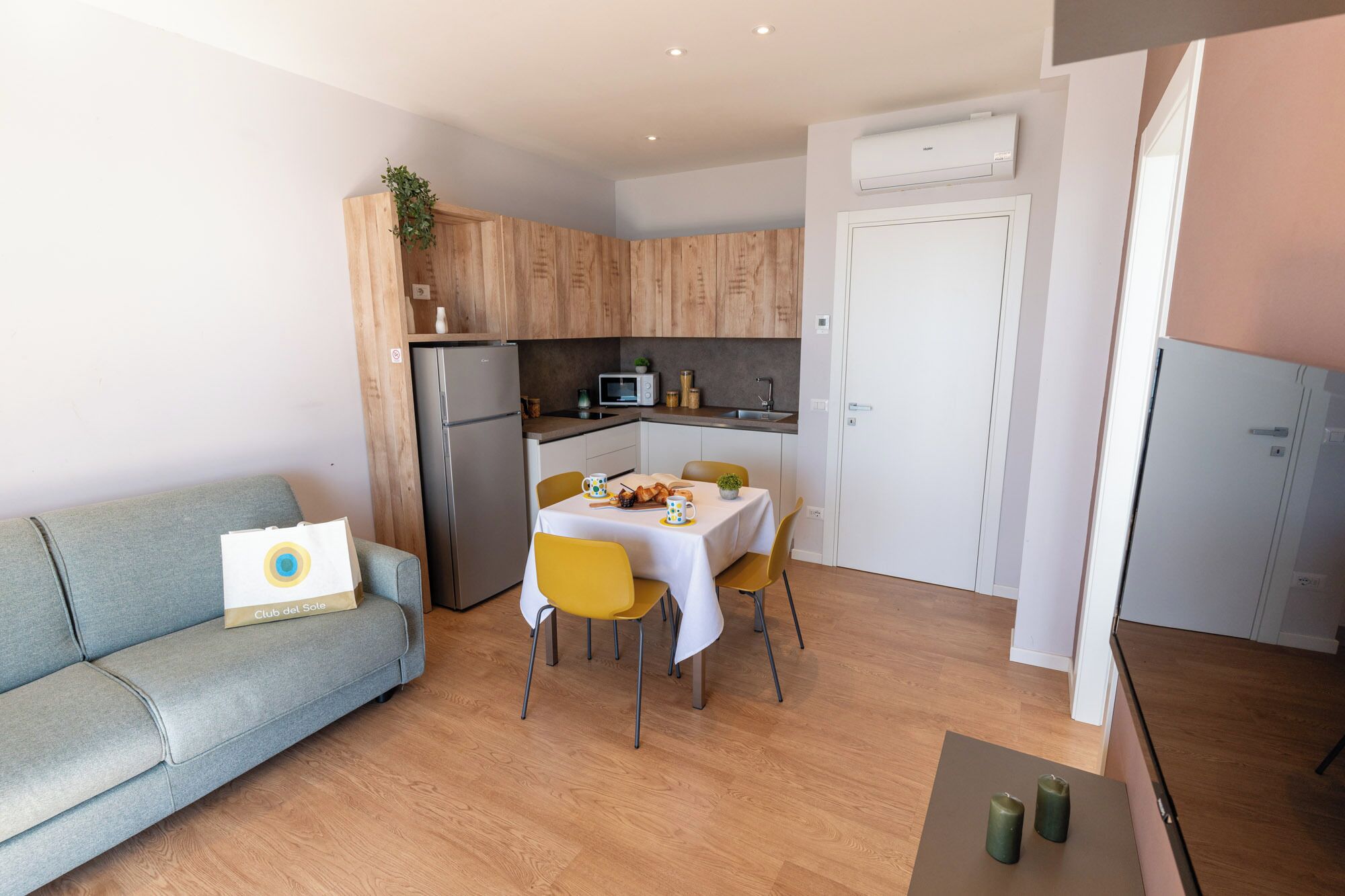 Un espacio habitable compacto con kitchenette, una zona de comedor con mesa y sillas, un sofá y una pequeña mesa de centro.