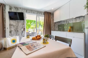 Una cucina moderna con forno integrato, un'area pranzo con tavolo apparecchiato per due e vista sul verde circostante.
