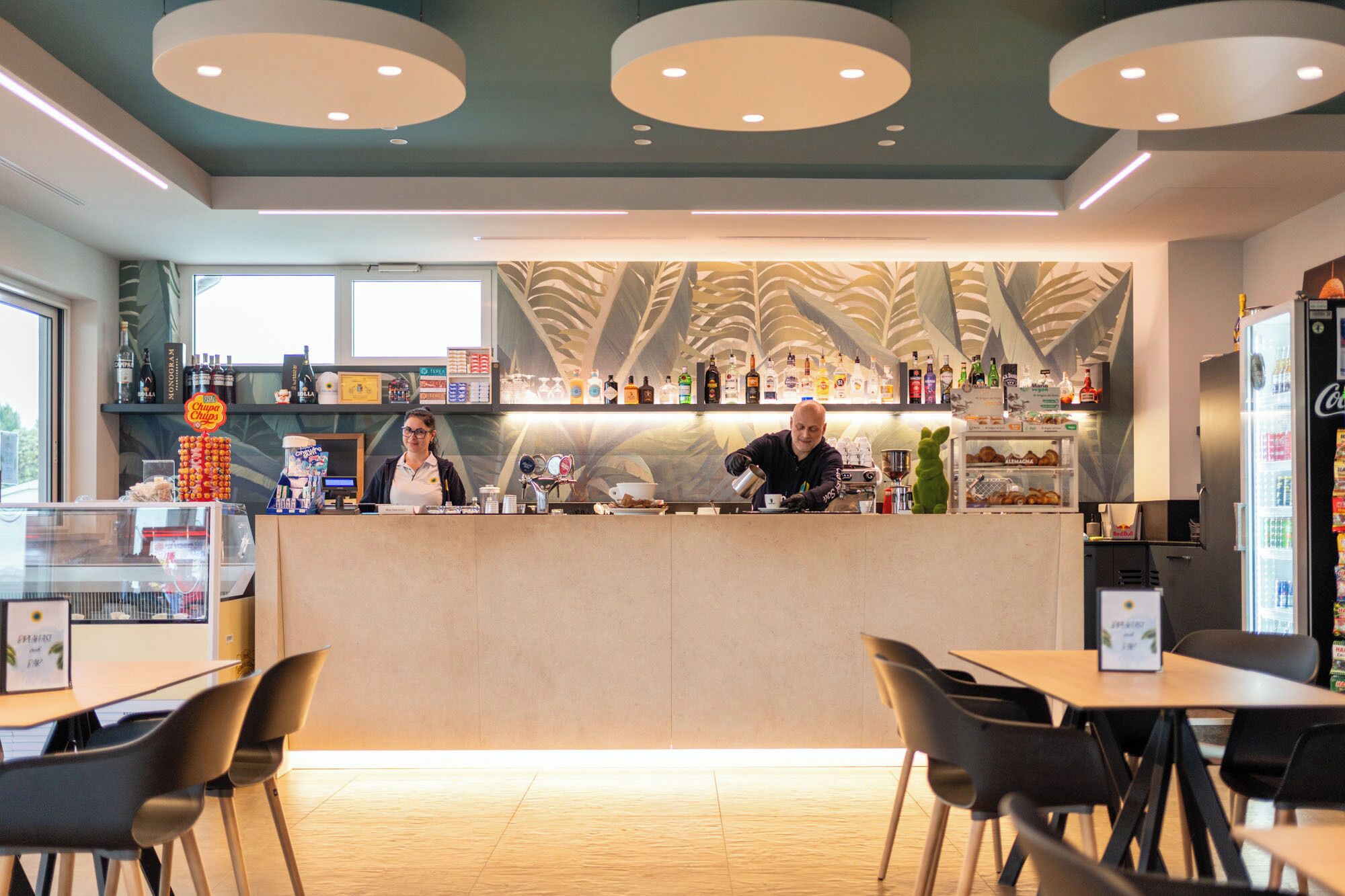 A modern cafe interior with a counter, bar area, and seating.