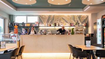 Interior de una cafetería moderna con mostrador, barra y mesas.
