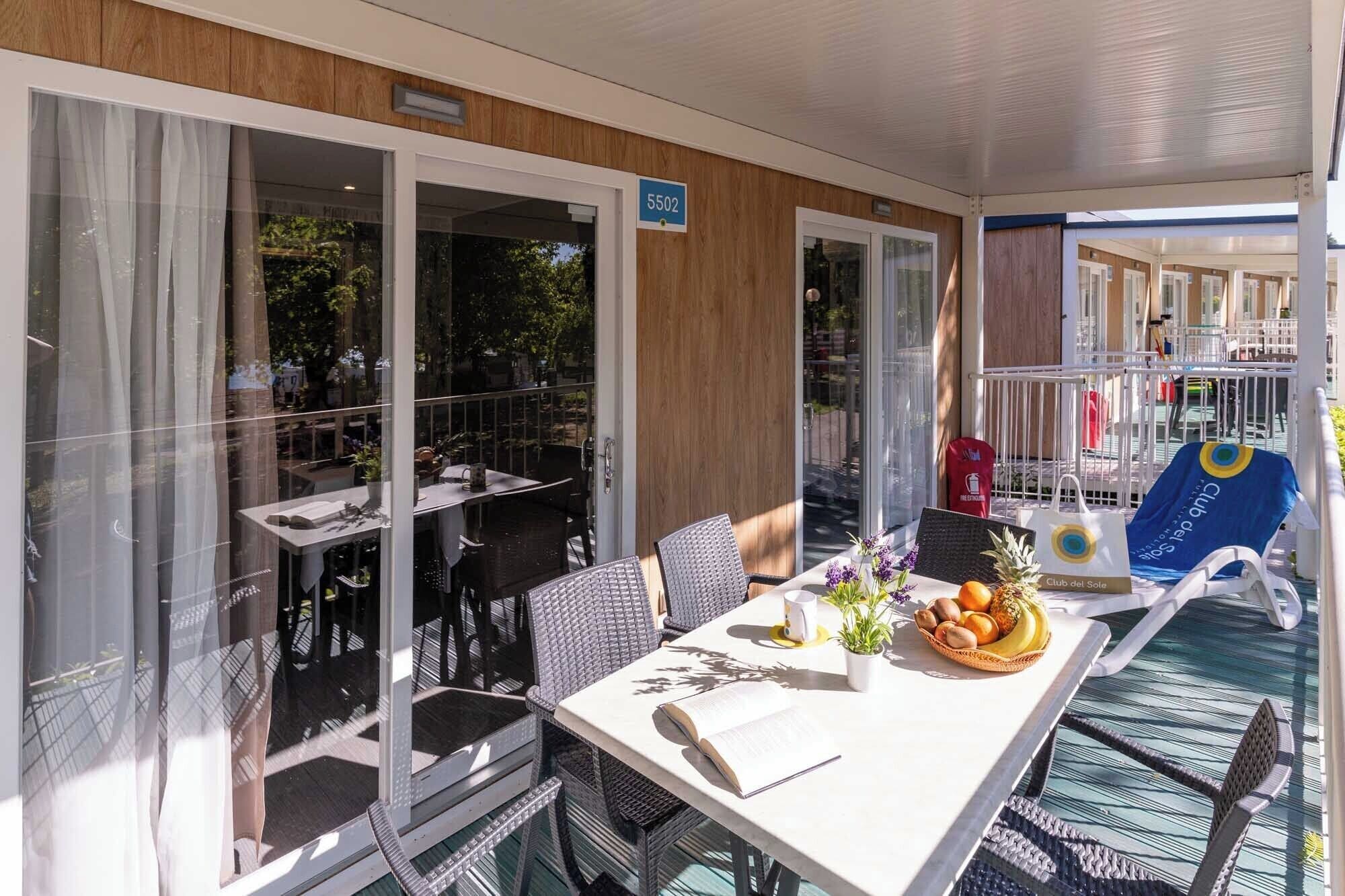 A sunlit outdoor dining area with a table, chairs, and a view of the surrounding greenery.