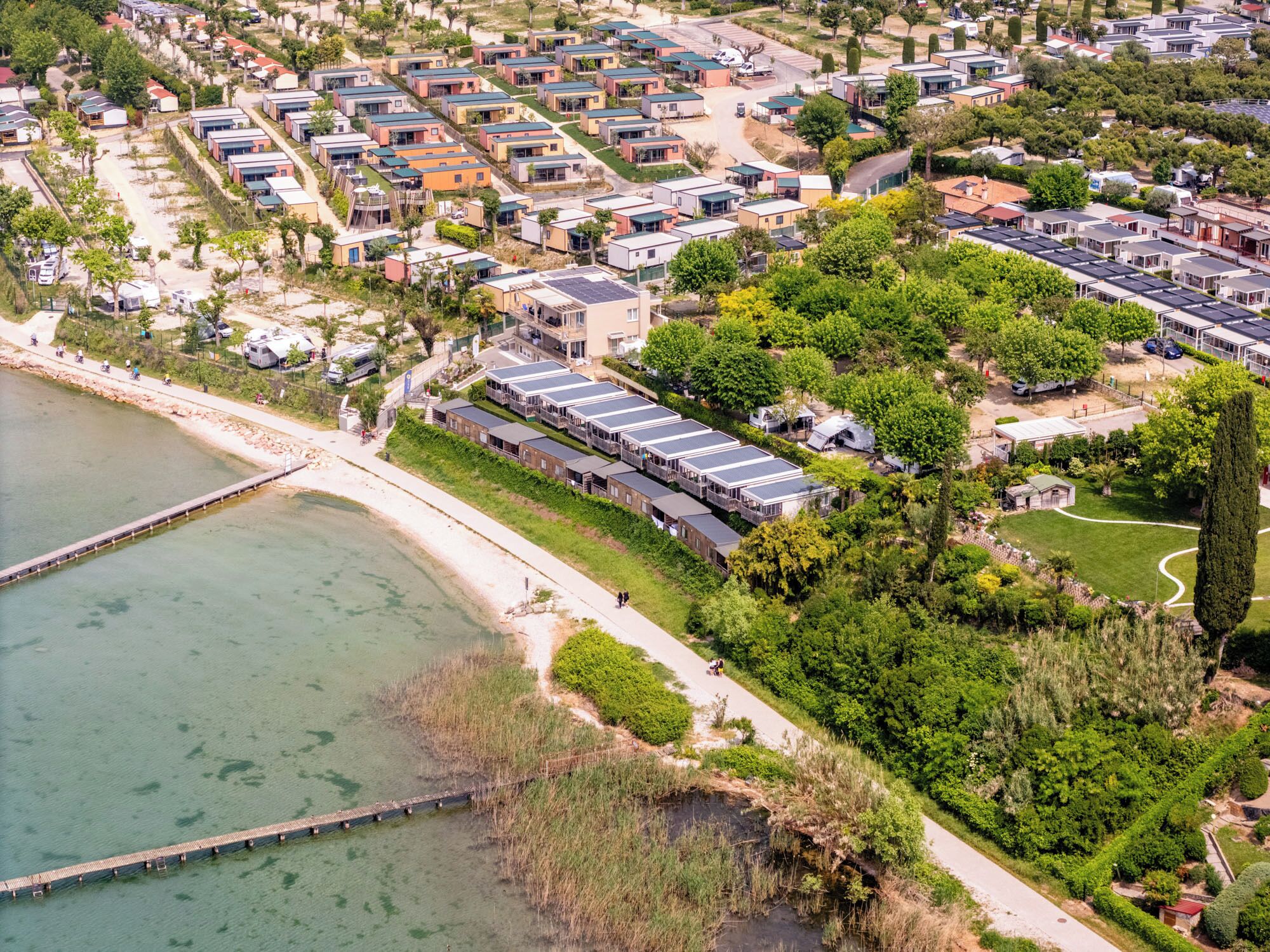 An aerial view of a coastal residential area with modern houses, a marina, and a bridge.