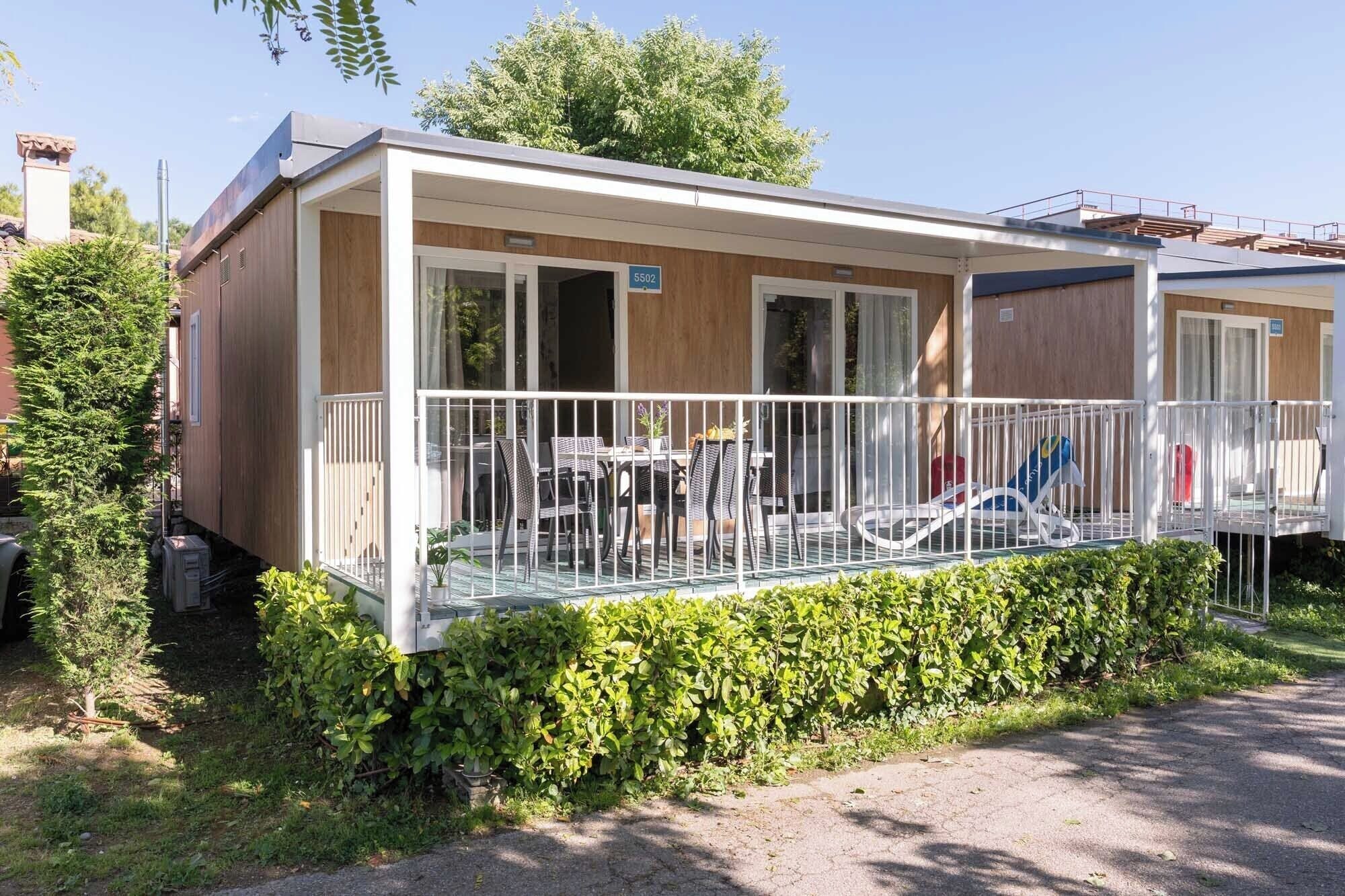 A mobile home with a balcony, outdoor seating, and a number sign.
