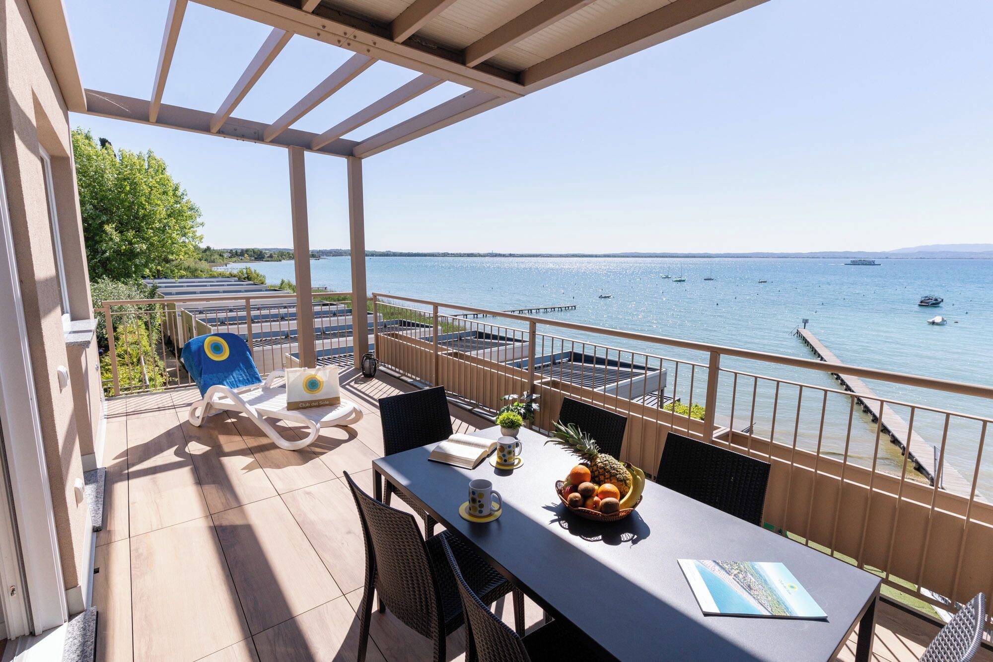 Una terraza con vista al mar, una mesa con una cesta de frutas y una silla.