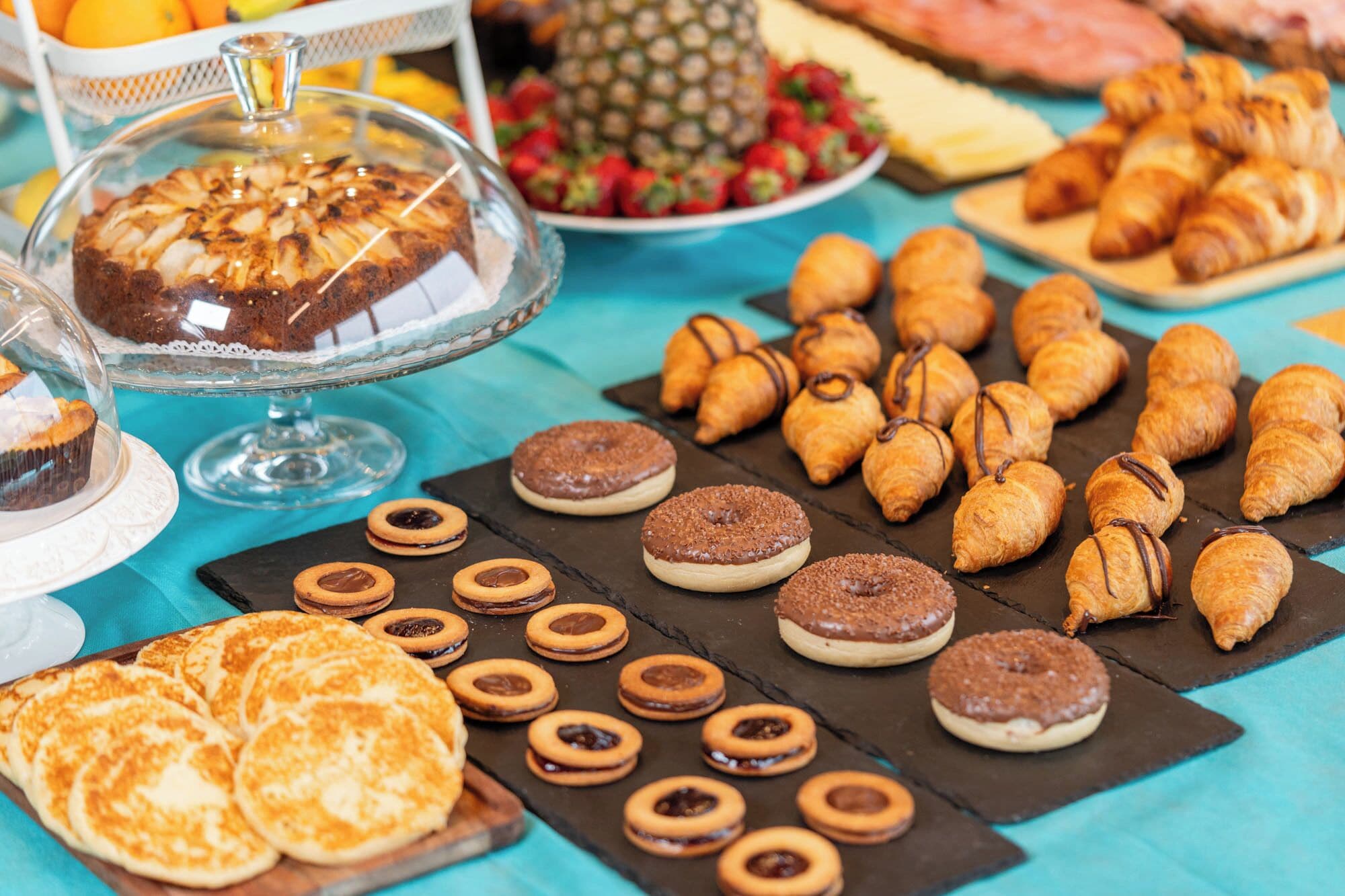 Variedad de productos horneados, como pasteles, galletas y una tarta, sobre una mesa.
