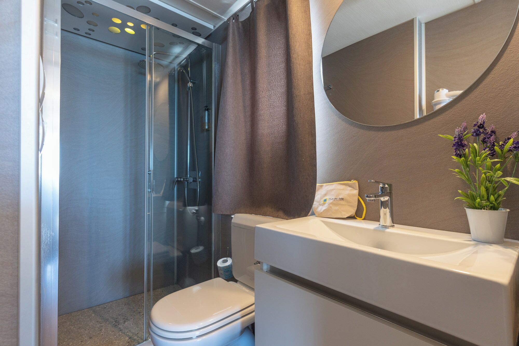 A bathroom with a shower, toilet, sink, and mirror.