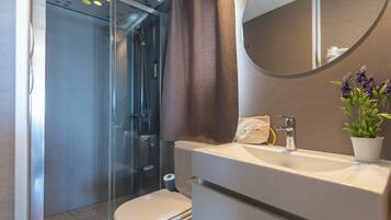 A bathroom with a shower, toilet, sink, and mirror.