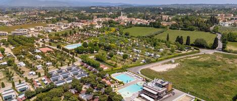 Vista aérea de una zona residencial con varios edificios, piscina y campos verdes.