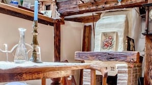 Una stanza rustica con un tavolo di legno, un candelabro e un camino in pietra.