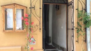Un edificio giallo con una porta in legno, una finestra con il menu e una pianta in vaso.