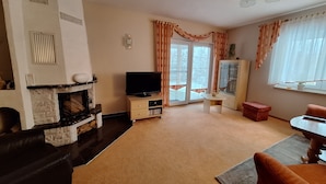 Ein Wohnzimmer mit Kamin, Fernseher und Essbereich.
