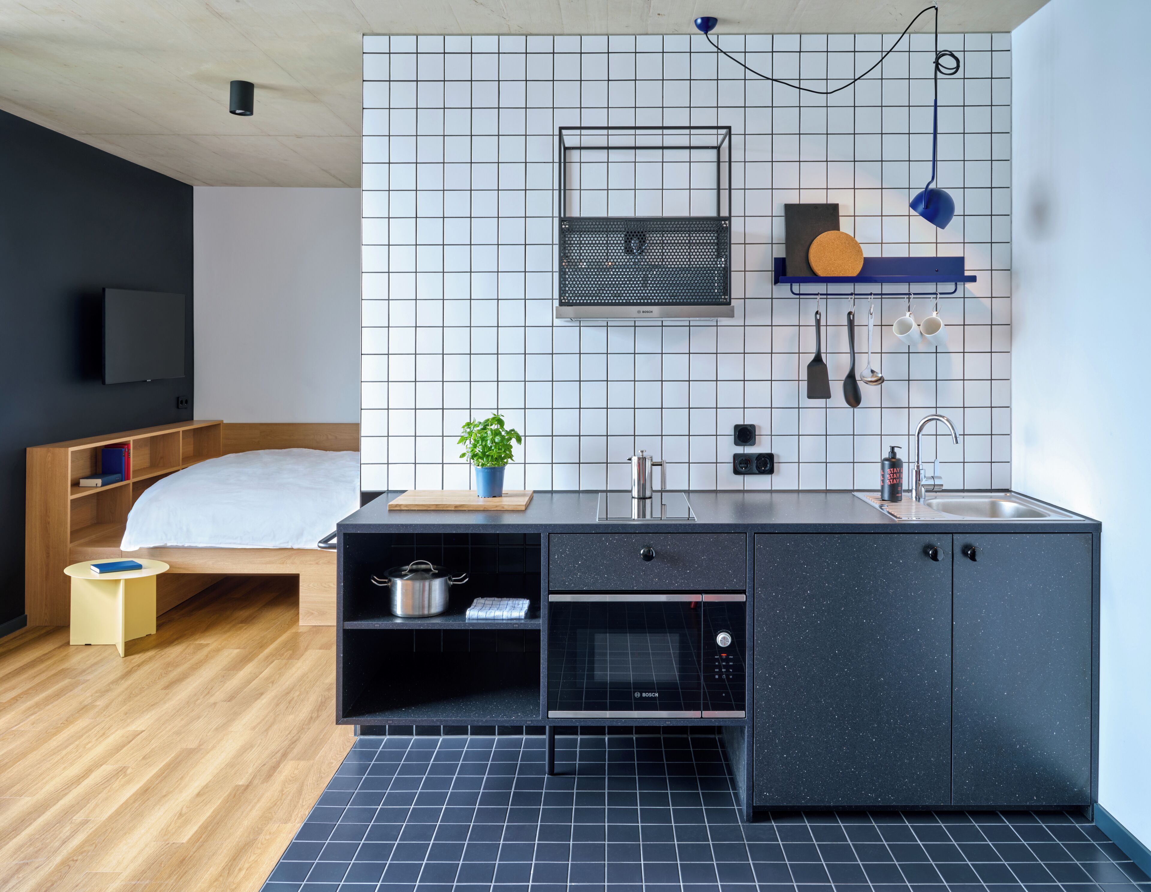 Een compacte keuken met een Bosch oven, een spoelbak en een klein aanrecht met een plant.