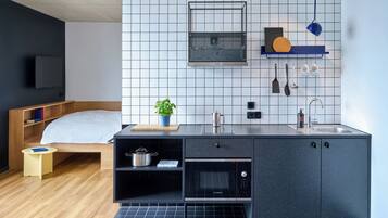 Een compacte keuken met een Bosch oven, een spoelbak en een klein aanrecht met een plant.