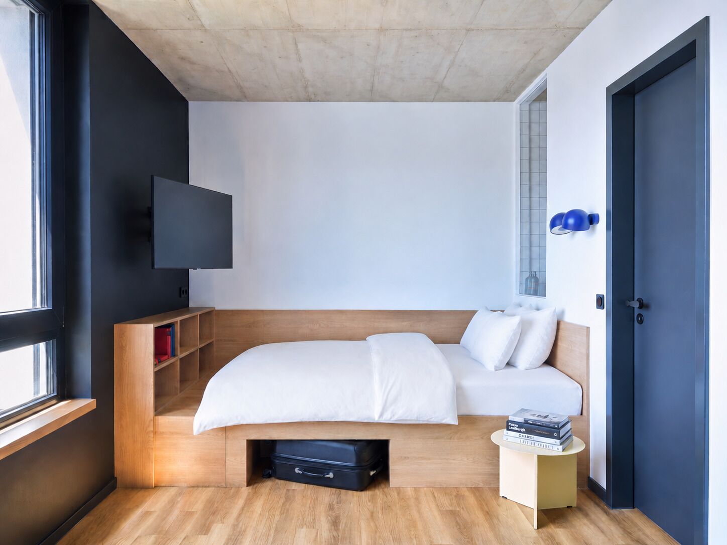 Une chambre d’hôtel moderne équipée d’un lit, d’une télévision, d’une table de chevet et d’une fenêtre.