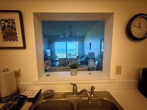 Eine Küche mit Blick auf ein Wohnzimmer, einen Essbereich und einen Balkon mit Meerblick.