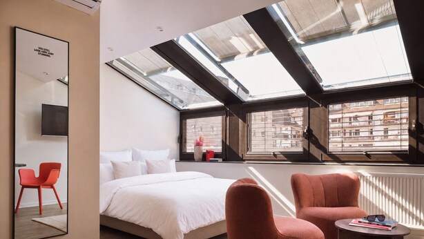 A modern bedroom with a skylight, a bed, a red chair, and a small table. - STAYERY Cologne Sülz (Cologne)