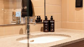 A bathroom with a sink, two bottles of shampoo, and a towel hanging on the wall.