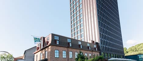 Un hotel con fachada de ladrillo moderno, techo plano y un edificio adyacente con grandes ventanales.