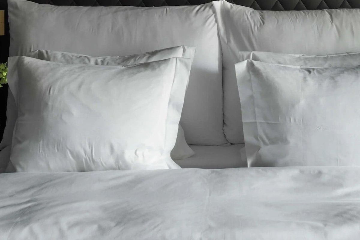 A bed with white bedding and pillows.